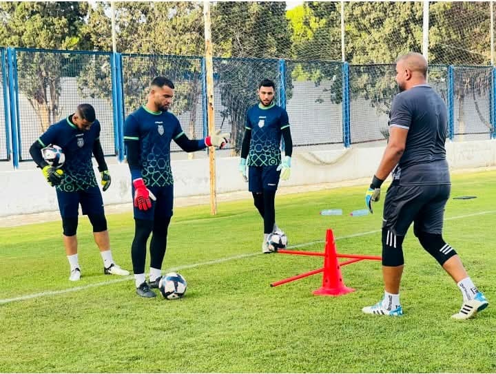 Raouf Rattouli entraînant trois gardiens de but lors d'un exercice avec plots sur le terrain.