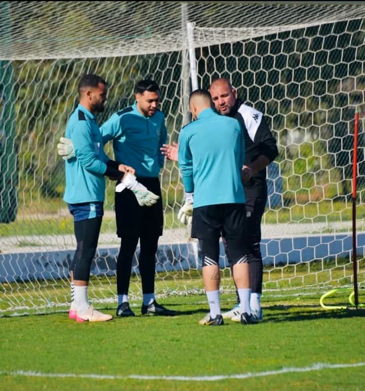 Raouf Rattouli avec quatre gardiens de but réunis près des buts, en pleine discussion pendant une séance d'entraînement.